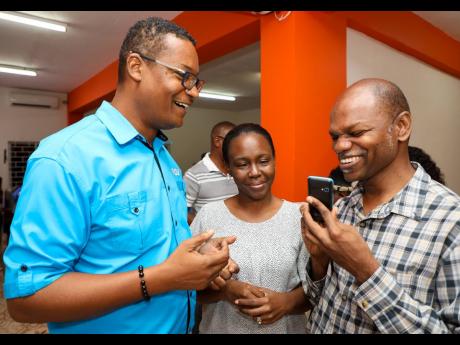From left: Whitney Fennell, senior director – B2C Sales and Distribution, Flow Jamaica, explains the capabilities of the voice-enabled KaiOS mobile phone to Kamika Braithwaite, information and training officer at the Jamaica Society for the Blind (JSB), and Conrad Harris, executive director at the JSB.
