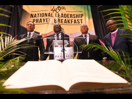Prime Minister Andrew Holness (left) and Bishop Conrad Pitkin (second left), custos rotulorum of St James and pastor of the Faith Temple Assemblies of God in Montego Bay, pray with Opposition Leader Dr Peter Phillips (second right) and Reverend Stanley Clarke, chairman of the National Leadership Prayer Breakfast Committee, during the National Leadership Prayer Breakfast held yesterday at The Jamaica Pegasus hotel in New Kingston.