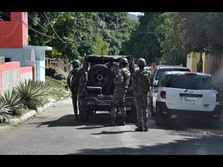 ABOVE: Soldiers on patrol in August Town, St Andrew, last Tuesday as tension builds in the community following two shootings late last year.