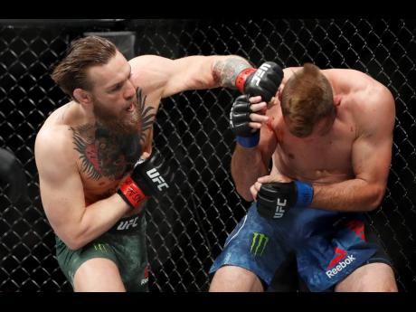 Conor McGregor (left) hits Donald ‘Cowboy’ Cerrone during a UFC 246 welterweight mixed martial arts bout Saturday, January 18, in Las Vegas. 