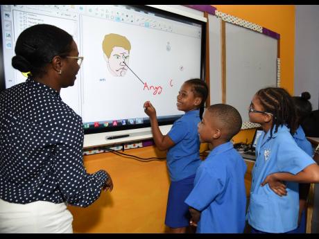 Jahssett Malcolm (left), senior accounts manager, Massy Technologies, shows students at the Port Royal Primary School how the interactive SMART board is used. Port Royal Primary and Infant School received US$10,000 through a grant from the Silicon Valley Charity Foundation to purchase the high-tech SMART board to enhance its information technology programme and improve the teaching and learning at the school.