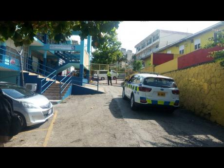 A guard keeps watch on the compound of Cornwall College where the dean of discipline was assaulted by a parent and others yesterday morning. 