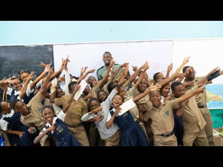 Students from the Granville Primary in Trelawny display the famous Usain Bolt ‘To The World’ pose with the great sprinter looking on in the background.  Seven schools in Trelawny, including Granville, have benefited from a donation of computer equipment through the Usain Bolt Foundation. 
