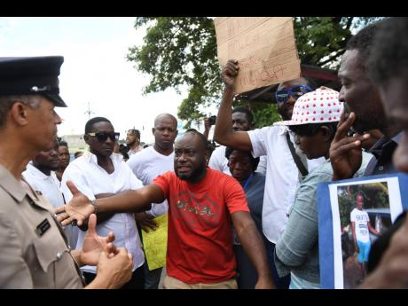 Assistant Superintendent Noel Daley listens yesterday to taxi operators who protested the police killing of a colleague in downtown Kingston on Monday. The demonstration took place along Spanish Town Road in the vicinity of the Denham Town Police Station.