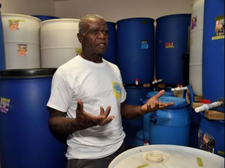 Winston Butler stands amid vats at his winemaking business, Butla’s Tropical Wines in Manchester.