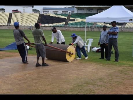 
President of the Trelawny Cricket Association Chester Anderson (right) and curator Samuel Palmer (second right) look on while groundsmen prepare the pitch at the Trelawny Multipurpose Stadium last Friday.
