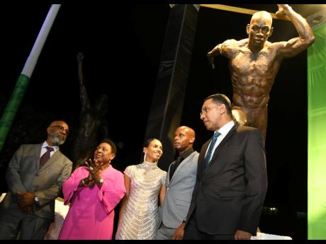 Olympian Asafa Powell (second right) poses with wife Alyshia (centre), sculptor Basil Watson (left), Sports Minister Olivia Grange (second left) and Prime Minister Andrew Holness in front of his statue which was unveiled at Independence Park on Sunday evening.