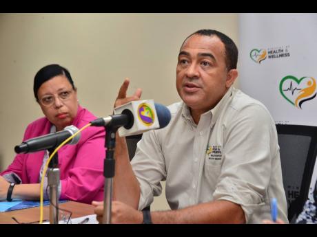 Bernadette Theodore-Gandi, PAHO-WHO representative to Jamaica, Bermuda and the Cayman Islands, listens as Minister of Health and Wellness Dr Christopher Tufton addresses a press briefing on the novel coronavirus on Monday.