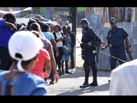 Police caution bystanders to avoid compromising a crime scene in in Stony Hill, St Andrew, on Wednesday morning. A man was shot dead and several others injured.