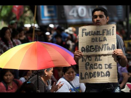 
Members of political parties and social movements protest the visit of an International Monetary Fund delegation, one with a sign that reads in Spanish ‘Get out of Argentina IMF. No to the debt payment’, in Buenos Aires, Argentina, on Wednesday, February 12. 