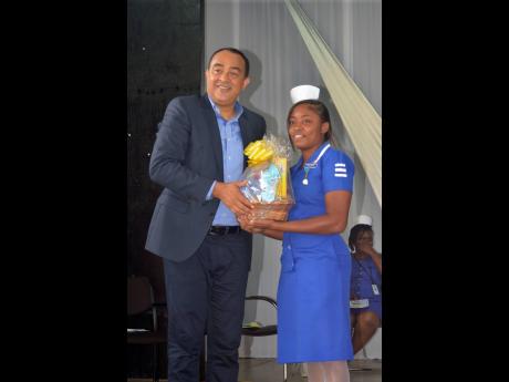 Health Minister Dr Christopher Tufton receives a token from Patricia Roberts, a fourth-year nursing student from the University of Technology’s Caribbean School of Nursing, during the school’s ninth annual striping ceremony for nurses, held at the St John’s Methodist Hall in Montego Bay on Friday.