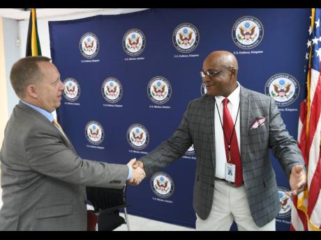 Deputy chief of mission of the United States Embassy, John McIntyre, (left) shakes hands with retired Lieutenant Colonel Gary Rowe, commissioner of corrections, at the handover ceremony of the Polygraph Unit to the Department of Correctional Services by the Embassy of the United States in Jamaica.
