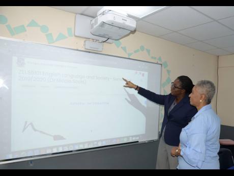 Dr Nicole Scott, deputy dean of the Graduate School of Education, The Mico University College, demonstrates the use of a smart projector to Sharon Wolfe, director of alumni affairs and development, at the official launch of the college’s SMART Room on Tuesday. 