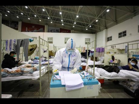 A medical staff member works near COVID-19 patients recuperating in a temporary hospital converted from an exhibition centre in Wuhan in central China’s Hubei province. The hospital, one of the dozen of its kind built in Wuhan, hosts COVID-19 patients with mild symptoms. 