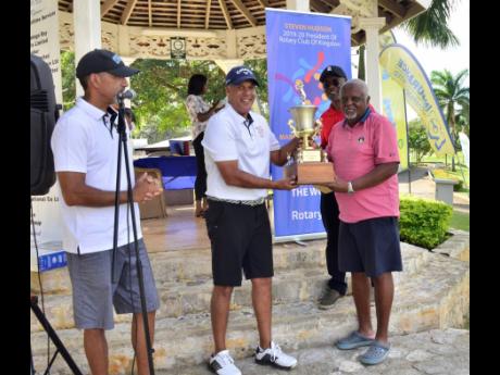 
Chairman of the Rotary Club of Kingston’s Annual Charity Golf Tournament Committee and past president of the club, Richard Josephs (left), looks on as club president Steven Hudson (second left) presents the winner’s trophy to Teddy Richards. In the background is the club’s immediate past president and member of the golf committee, Linval Freeman.