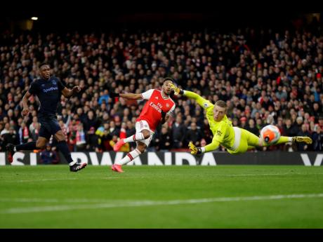 Arsenal’s Pierre-Emerick Aubameyang (centre) scores his side’s second goal as Everton’s goalkeeper Jordan Pickford (right) fails to save the ball during their English Premier League match at the Emirates Stadium in London, England, yesterday.