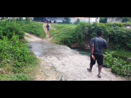 A man walks along a path where Kimona Whyte was washed away after a river overflowed its banks on Monday. Her body was found at sea by the Coast Guard.