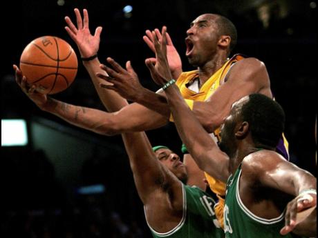 In this February 23, 2007 file photo, Los Angeles Lakers’ Kobe Bryant (with ball) goes up for a shot between Boston Celtics’ Paul Pierce (left) and Al Jefferson during the first half of an NBA basketball game in Los Angeles.