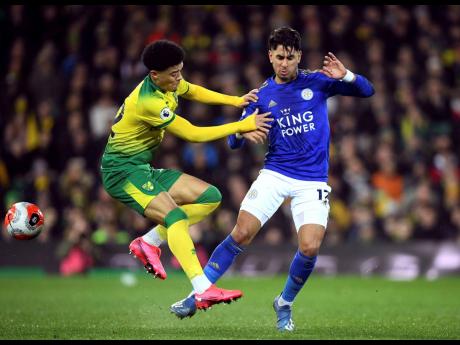 Norwich City’s Jamal Lewis (left) and Leicester City’s Ayoze Perez battle for the ball during the English Premier League  match at Carrow Road yesterday. 