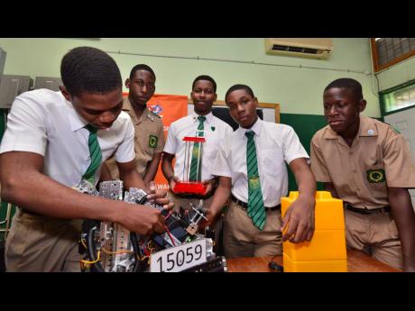 David Lynch makes an adjustment to Calabar’s title-winning creation while teammates (from second left) Tyrique Murray, Joel Tulloch, Raheem Ford, and Alex Hutchinson look on yesterday. Calabar won the FIRST Tech Robotics Championship on Saturday. 