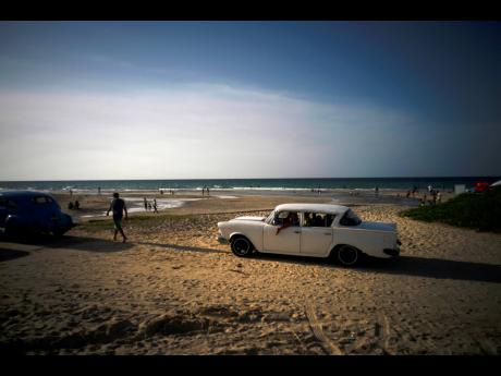 In this July 18, 2019 file photo afamily arrives on the beach in a classic American car on the outskirts of Havana, Cuba.