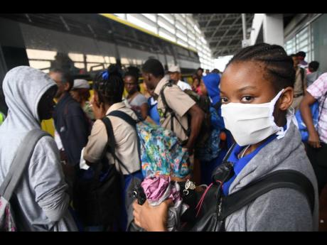 Students wear protective gear against the spread of the novel coronavirus at the Half-Way Tree Transportation Centre on Wednesday. Two cases of COVID-19 have been confirmed in Jamaica.