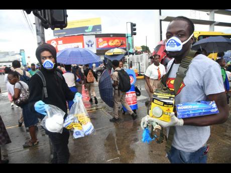 Hawkers sell protective gear against the outbreak of the novel coronavirus outside the Half-Way Tree Transportation Centre yesterday. Thousands of Jamaicans have begun wearing face masks and gloves and have also been stocking up on cleaning agents, leaving many shelves empty. 