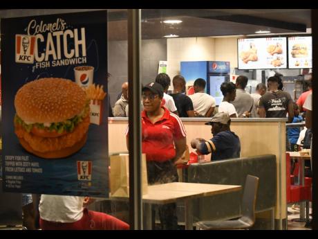 Foodies flock the Cross Roads branch of KFC on Monday night. The high-traffic restaurant chain said that effective Wednesday, it would be observing the Government’s 20-person restriction and would allow only takeout and drive-through customers. Social-distancing markers will also be placed on the floor.