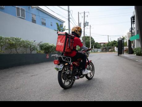 A QuickPlate motorcyclist exits 80 LMR in St Andrew on Wednesday. The food-delivery outfit has noticed an increase in user registration amid the local spread of COVID-19 in Jamaica and intends to launch a grocery-delivery offering early next week.