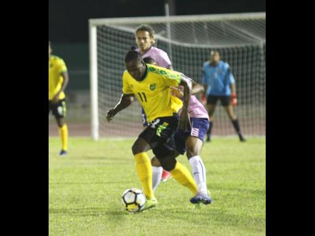 Jamaica’s Jourdaine Fletcher (front) turns with the ball away from Bermuda’s Reginald Lamb during their international friendly match at the Montego Bay Sports Complex on Wednesday, March 11. The game was played just a day after the nation officially discovered its first COVID-19 patient.