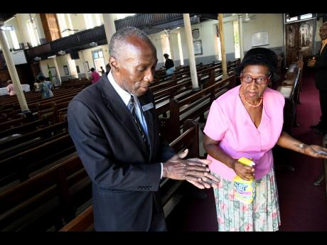 Astley Thomas and Coralee Fearon sanitising their hands at East Queen Street Baptist Church in Kingston on Sunday.