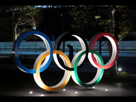 A man is seen through the Olympic rings in front of the New National Stadium in Tokyo, yesterday. 