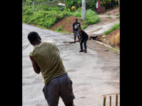 Young men at Junction crossroads, St Catherine, play a game of cricket in the streets to help pass the time as COVID-19 has turned many districts and villages into ghost towns.