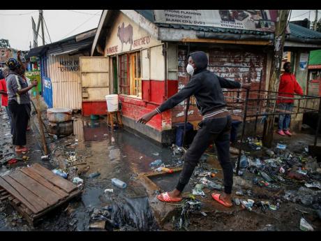 A boy wears a mask as a preventative measure against the spread of the new coronavirus, as he navigates a flood of water mixed with garbage following heavy rains, in the Kibera slum, or informal settlement, of Nairobi, Kenya, Thursday, March 26. 