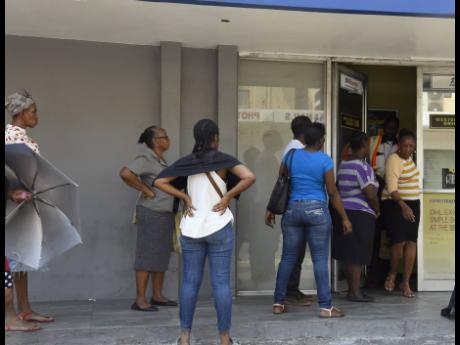 Customers queue up outside a Western Union outlet in Cross Roads, St Andrew, as business places impose social-distancing rules to curb the spread of COVID-19. As the coronavirus outbreak worsens globally, remittances to the country are reportedly falling.