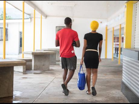 International students of The University of the West Indies, Mona, walk the generally empty corridors of the institution last Thursday. Despite an announcement that all students should return home, the two have opted to remain on campus.