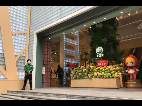 A store employee waits outside for customers at a re-opened retail street in Wuhan in central China’s Hubei province on Monday. Shopkeepers in the city at the centre of China’s virus outbreak were reopening Monday but customers were scarce after authorities lifted more of the anti-virus controls that kept tens of millions of people at home for two months.