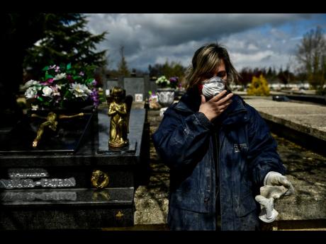 Undertaker Mari Carmen Serrador, 53 years old, protecting herself with a mask at Salvador cemetery during the coronavirus outbreak, near to Vitoria, northern Spain, on Monday. (AP)