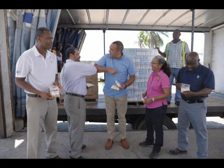 Minister of Health and Wellness Dr Christopher Tufton (third right) shares an elbow bump with Jamaica Flour Mills Managing Director Derrick Nembhard during a hand over of flour and cereal to communities under quarantine as a result of the COVID-19 pandemic. Looking on are Permanent Secretary in the Ministry of Labour and Social Security Colette Roberts-Risden (second left) and  Jamaica Flour Mills supervisors Wayne Owen (left) and Lenford Walton.