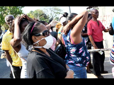 Members of the public wait outside the Comprehensive Health Centre on Slipe Pen Road in Kingston on Friday, March 27. However, social distancing guidelines appear to be lost on them as they stand close to each other before entering the health facility. With the onset of the highly contagious COVID-19 members of the public have been urged to observe social distancing protocols.