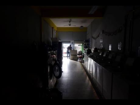 Laundromat owner Jesus Vazquez pauses before closing his shop to comply with the government’s curfew aimed at curbing the spread of the new coronavirus, which is shuttering all non-essential businesses for two weeks in San Juan, Puerto Rico. 