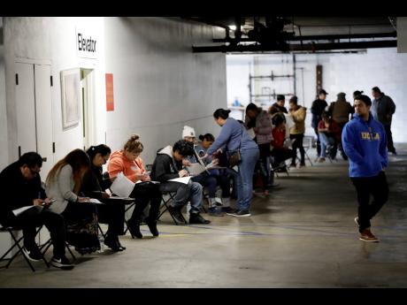 AP
In this March 13, 2020 file photo, unionised hospitality workers wait in line in a basement garage to apply for unemployment benefits at the Hospitality Training Academy in Los Angeles. 