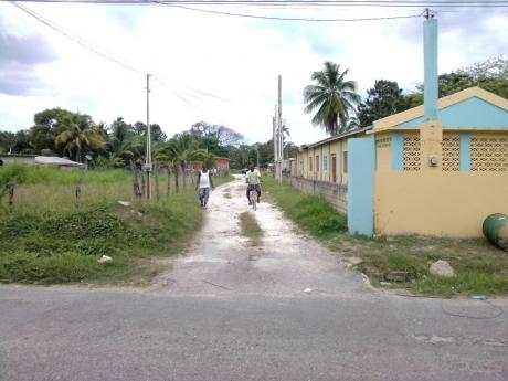 Two residents traverse a lane in George’s Plain, Westmoreland, where a now-deceased COVID-19 patient lived.