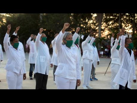 A brigade of health professionals, who volunteered to travel to the West Indies, raise their right fist as they sing their country’s national anthem in Havana, Cuba, on March 28. The medical team is now in the dual-island country Saint Kitts and Nevis to assist local authorities with an upsurge of COVID-19 cases.