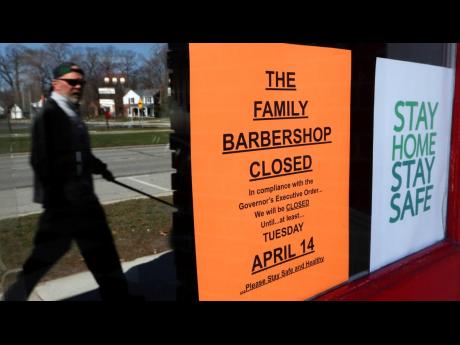 A pedestrian walks by a closed business, The Family Barbershop, in Grosse Pointe Woods, Michigan, on Thursday, April 2, 2020.