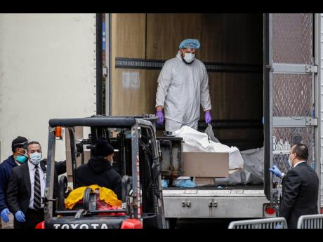 A body wrapped in plastic is loaded onto a refrigerated container truck used as a temporary morgue by medical workers wearing personal protective equipment due to COVID-19 concerns last week at Brooklyn Hospital Center in the Brooklyn borough of New York.