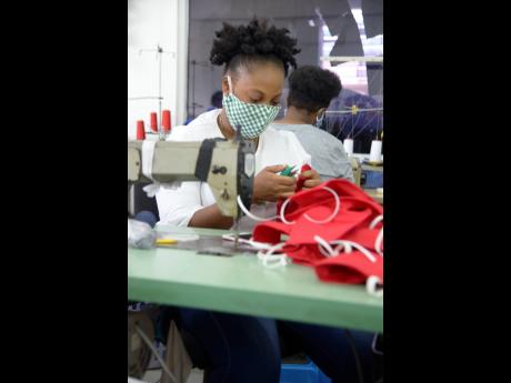 Sobrena Powell, embroidery assistant, cutting and stringing masks at Apparel Wearhouse on Red Hills Road, St Andrew. 