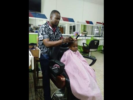 Marlon Gray, head of the Clarendon Barbers, Hairdressers and Nail Tech Association, cutting a client’s hair.