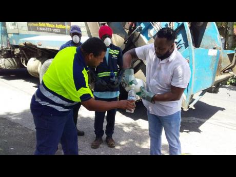 Patrick Marshall, senior public cleansing inspector, dispensing a cleansing agent to workers.