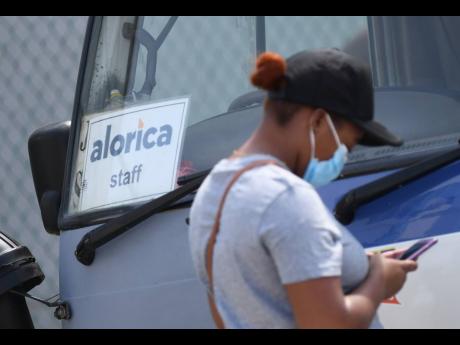 An employee of the Alorica call centre in Portmore, St Catherine, stands next to the staff bus outside the BPO facility.